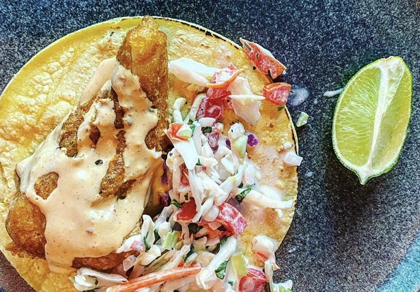 a fish taco on a plate with a slice of lime