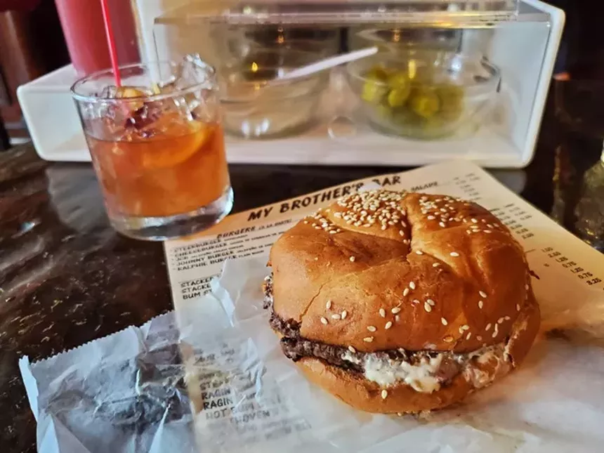 a cheeseburger on parchment paper with an old fashioned