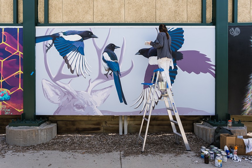 artist painting a mural of birds