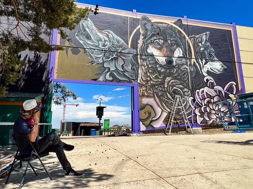 artist looks at his mural of wolves