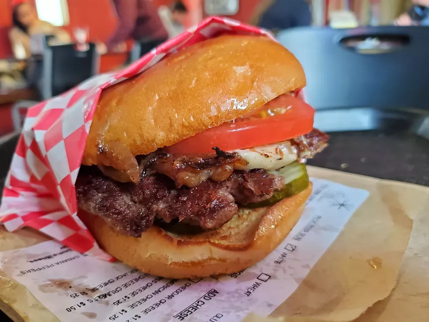 a cheeseburger with pickles and tomatoes