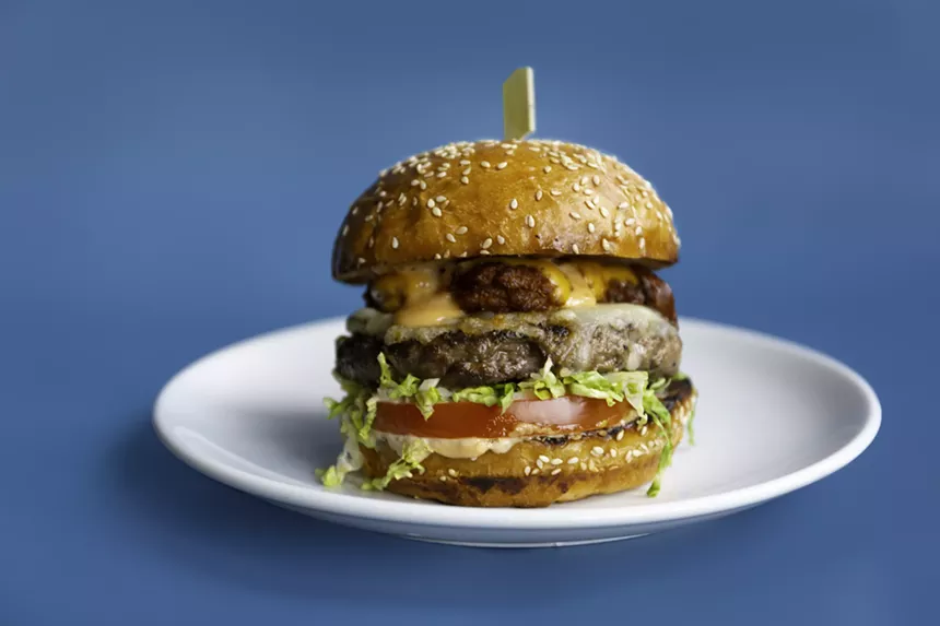 a cheeseburger on a sesame bun with lettuce and tomato