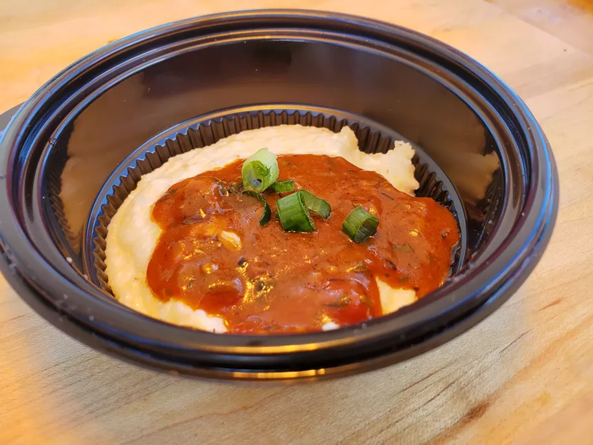 a bowl of grits with a red sauce on top