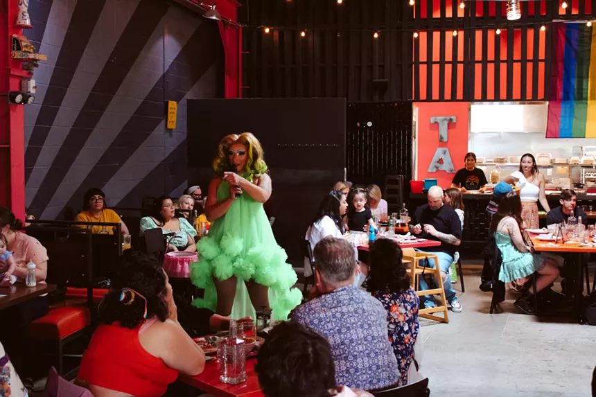 drag queen in green talking to crowd