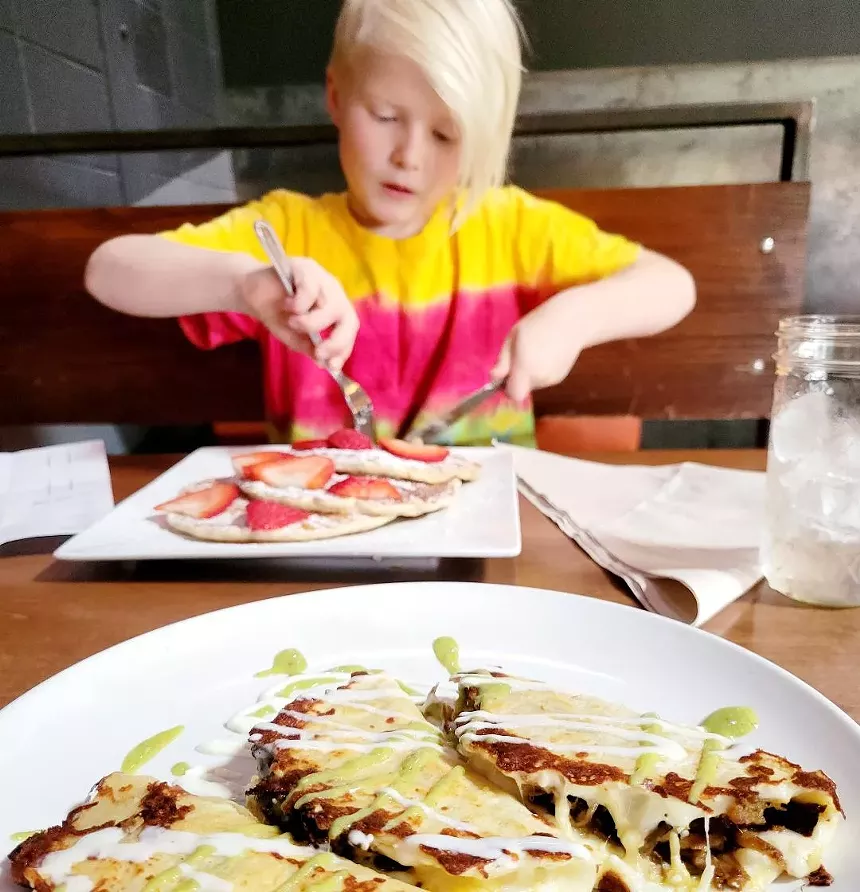 kid eating pancakes with tacos in front