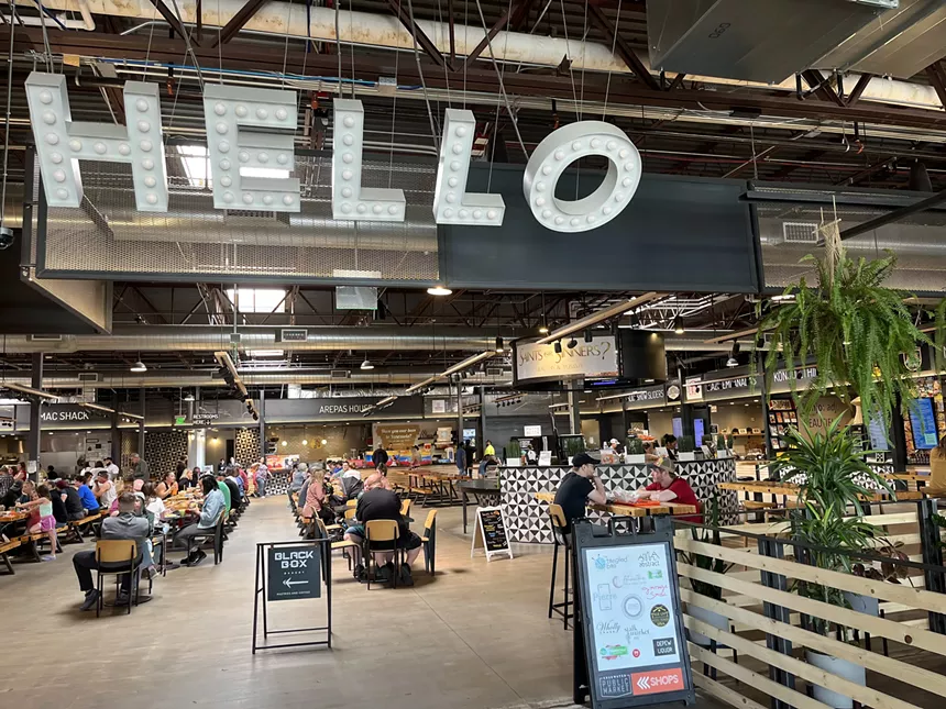 large letters that spell hello hanging from the ceiling of a food hall
