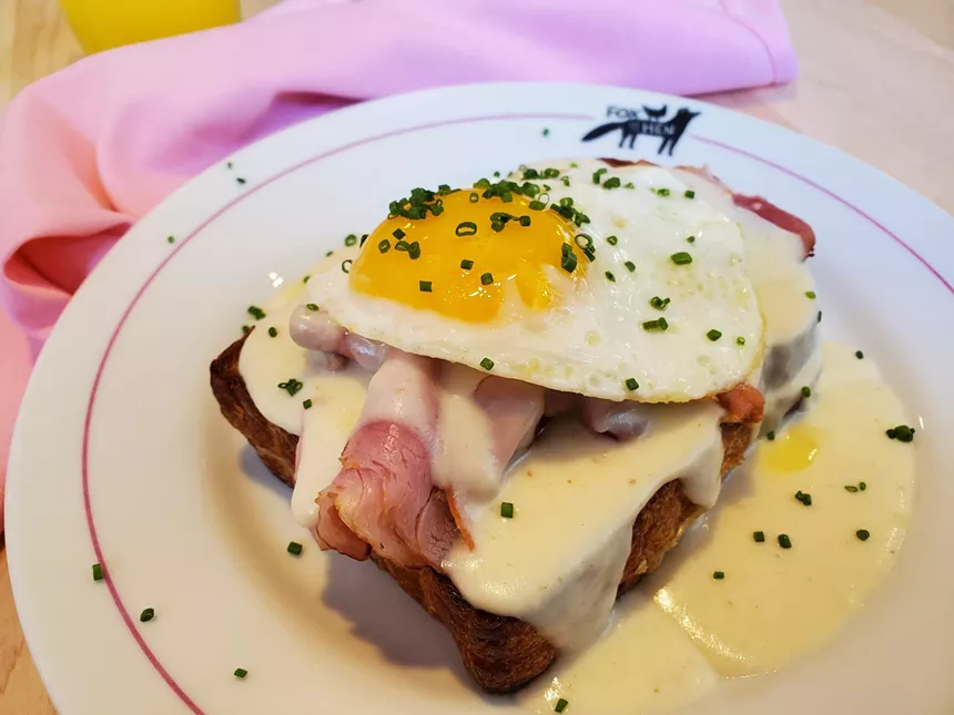 a thick piece of bread topped with a white sauce, ham and egg