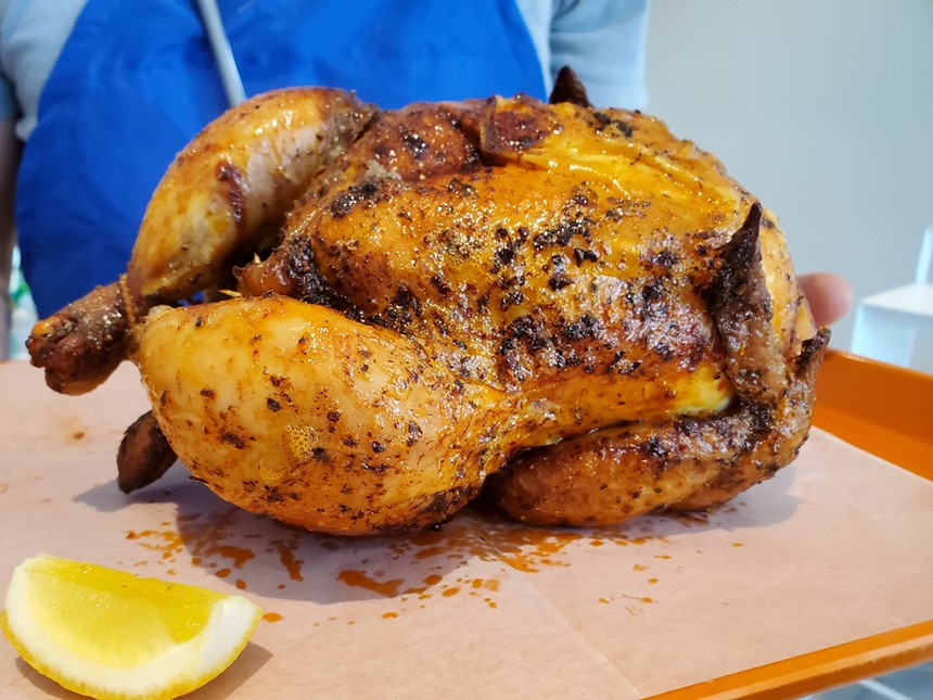 a whole rotisserie chicken on a try with a slice of lemon