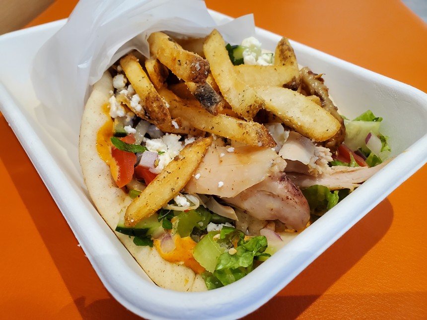 a pita sandwich with fries in a to-go box