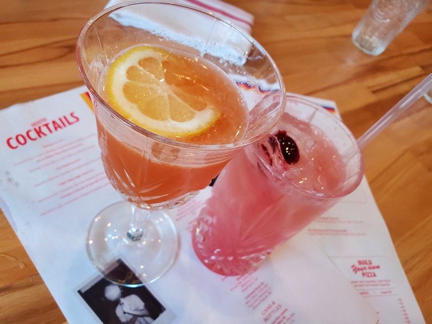 an orange cocktail with a lemon slice in it next to a pink cocktail with a cherry in it