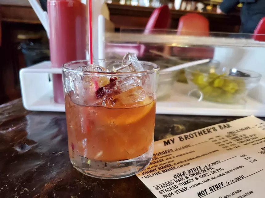 a cocktail in a short glass on a table next to a menu