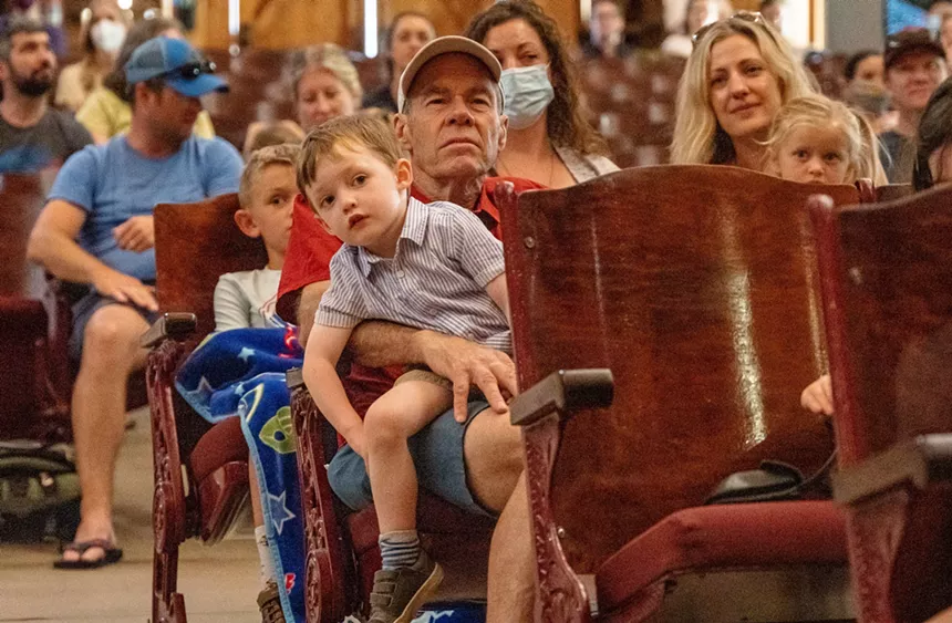 kids and adults in auditorium listening to music.