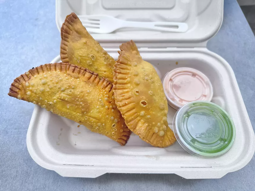 three fried pastries in a to-go box