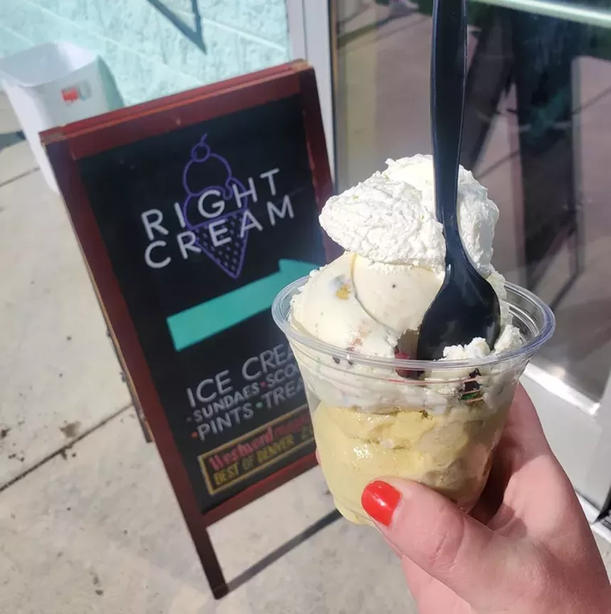 a hand holding ice cream in a cup