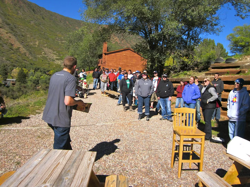 people standing in a line outside near a small hill