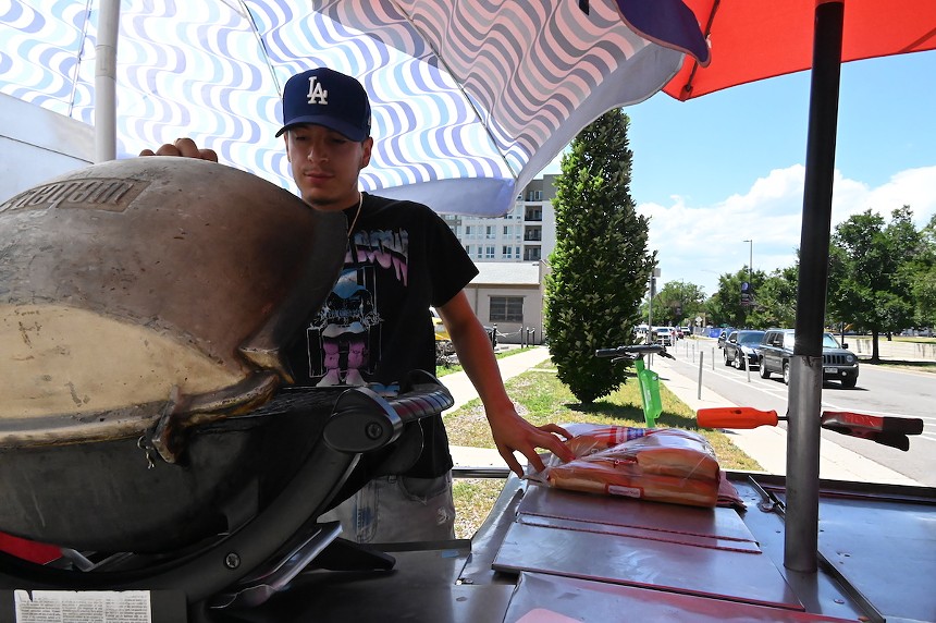 Marcello Rodriguez opens his Weber grill as he cooks hot dogs outside the Lindsey-Flanigan Courthouse.