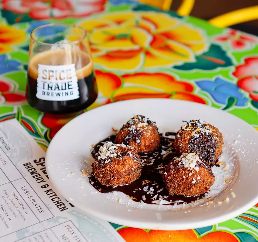 Tres leches arancini on a plate with beer.