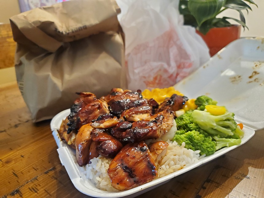 an open styrofoam takeout box filled with chicken, rice and vegetables