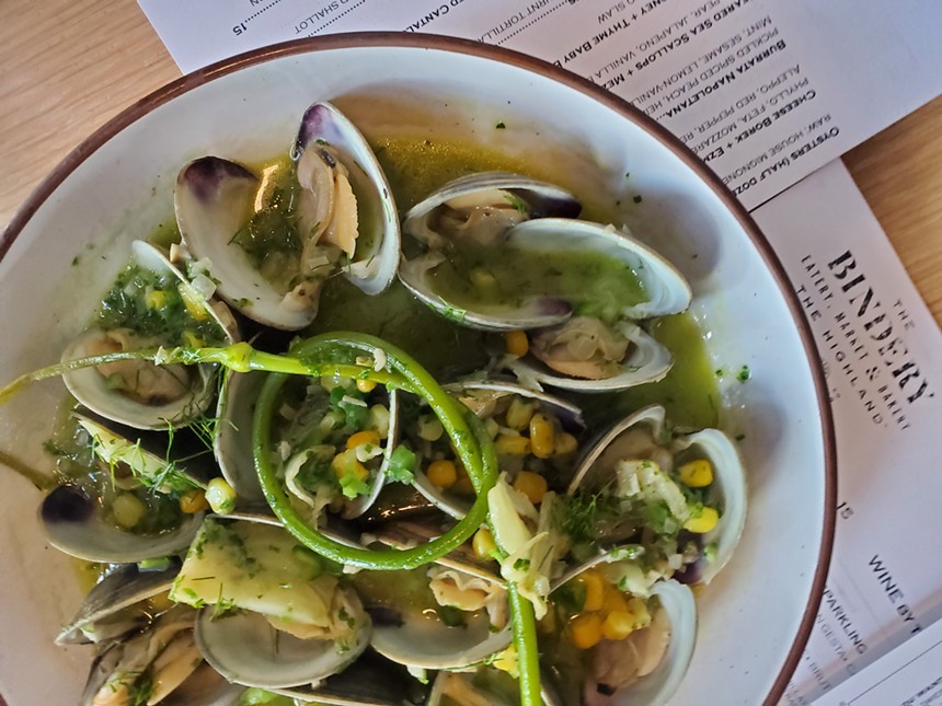 a bowl of clams with green garlic on top