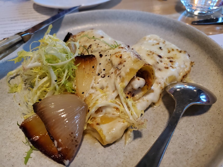 a piece of charred onion, greens and pasta with white cheese on top