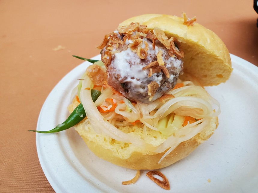a meatball on a bun with shredded vegetables