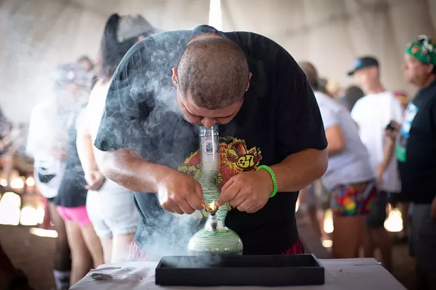 A man takes a large hit from a bong