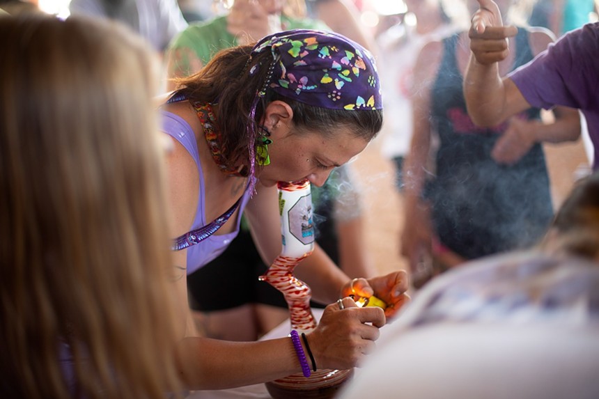 A woman in a bandana smokes weed from a bong