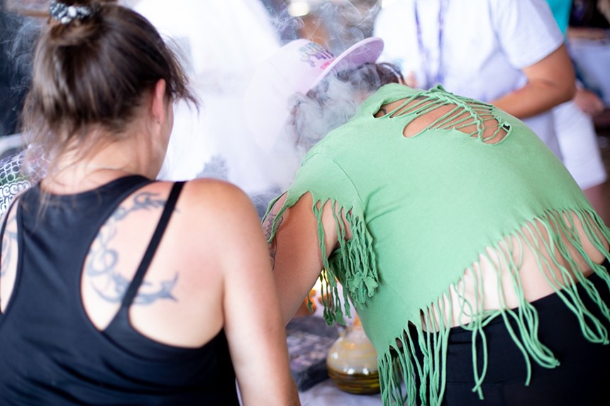 A woman blows smoke in between hits from a bong