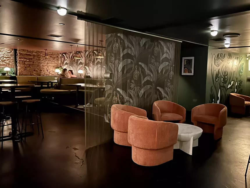 pink chairs inside a room with tropical wallpaper