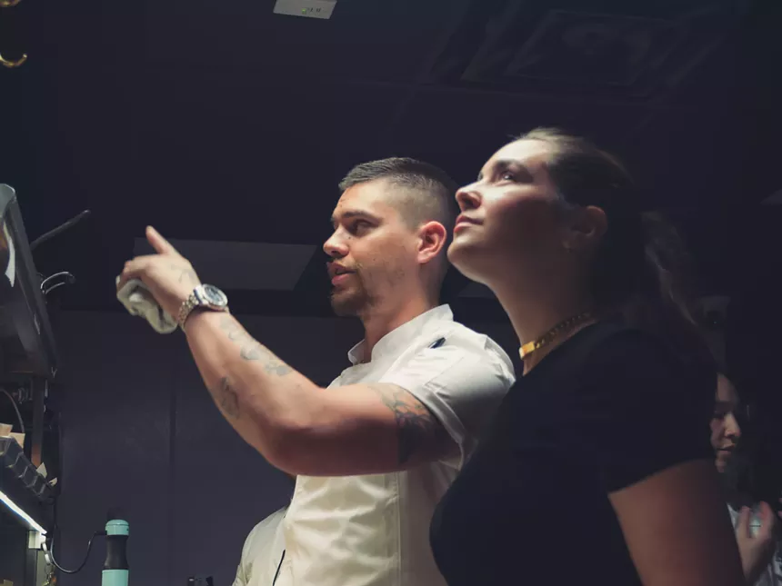 man in a white chef's coat next to a woman in a black t shirt
