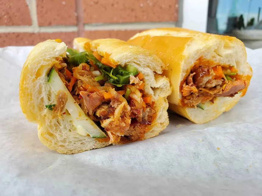 sandwich on a french roll with duck and vegetables
