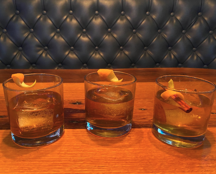 three cocktails in short glasses with an orange zest garnish