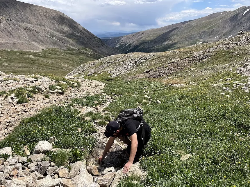 Bennito Kelty dips his hand in a stream along the DeCaLiBron loop near Alma, Colorado.