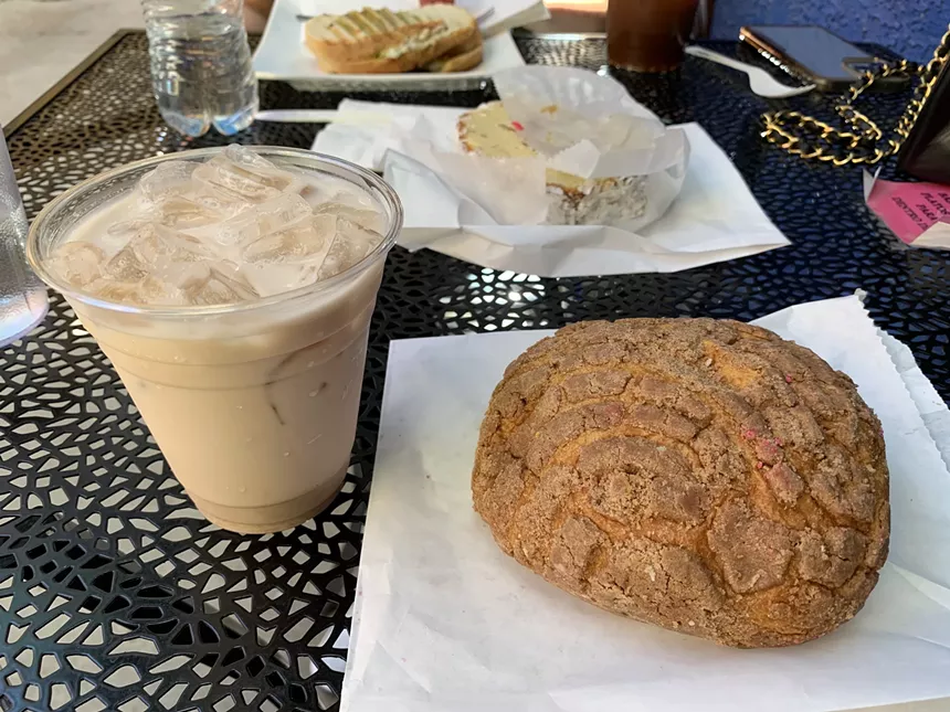 a cup filled with a coffee drink next to a round pastry