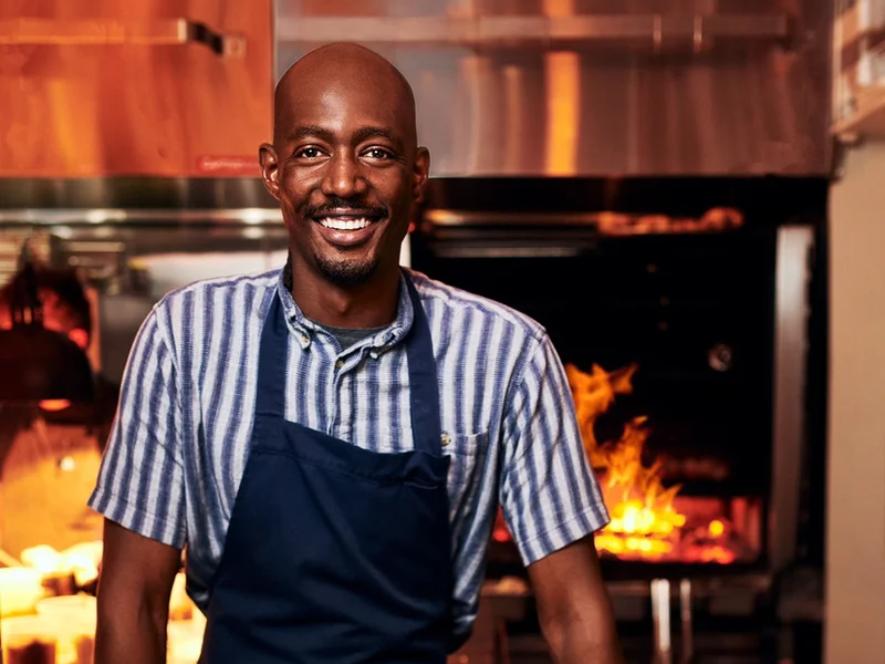 a man in an apron standing in a kitchen