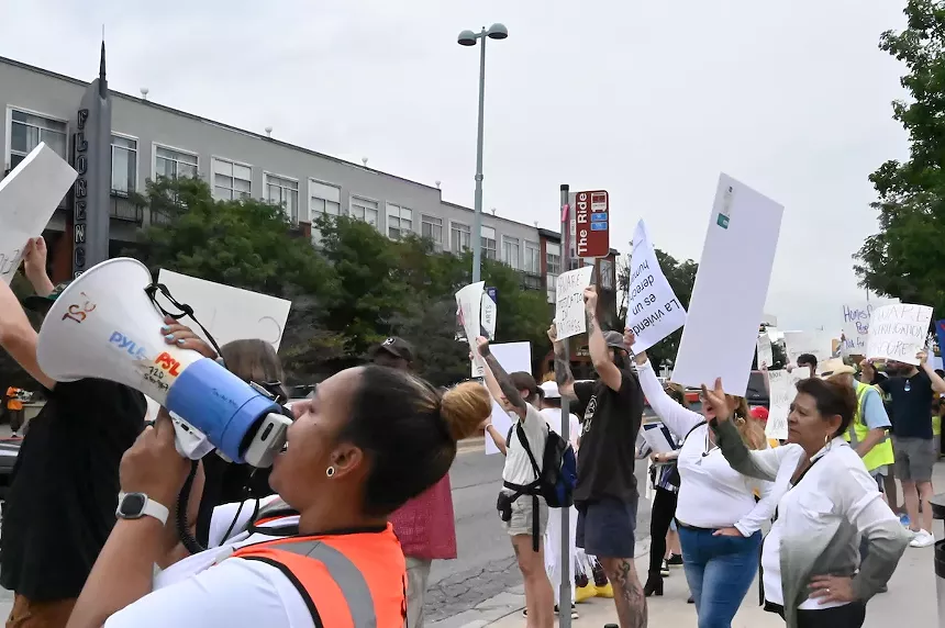 Protesters hold up signs and shout through a megaphone during a protest at Fletcher Plaza on East Colfax Avenue.