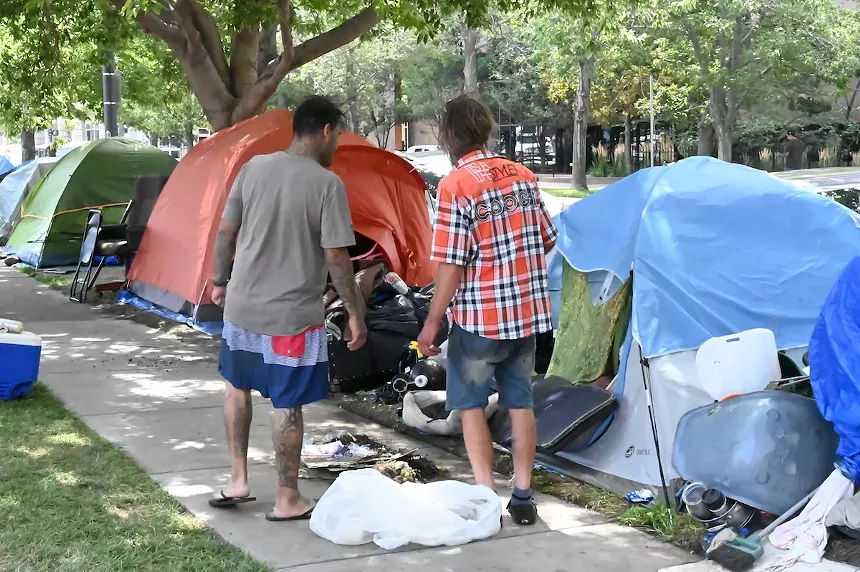 Two homeless people talk while cleaning out their tents on 17th Avenue and Logan Street.