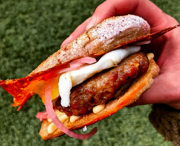 hand holding a sausage and egg sandwich