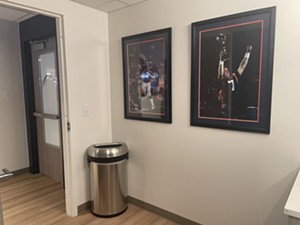 Two images of Broncos quarterback John Elway sit on a white wall.