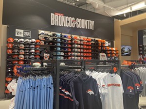 Under a sign saying "Broncos Country" sits tons of hats and shirts in Broncos colors.