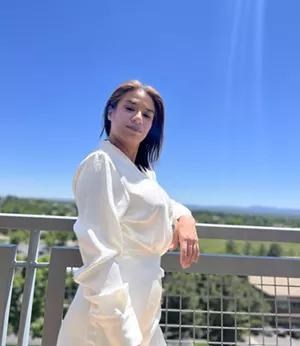 A woman in white stands on a ledge