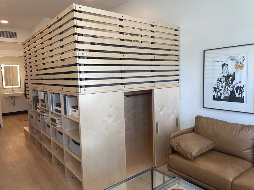A light wood platform bed with cube bookshelves underneath.
