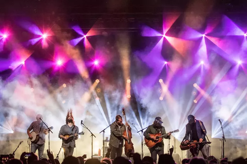 bluegrass musicians on a stage with purple and white lights