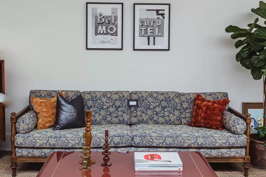 Couch and coffee table in front of white wall with two symmetrically positioned, small framed pictures.