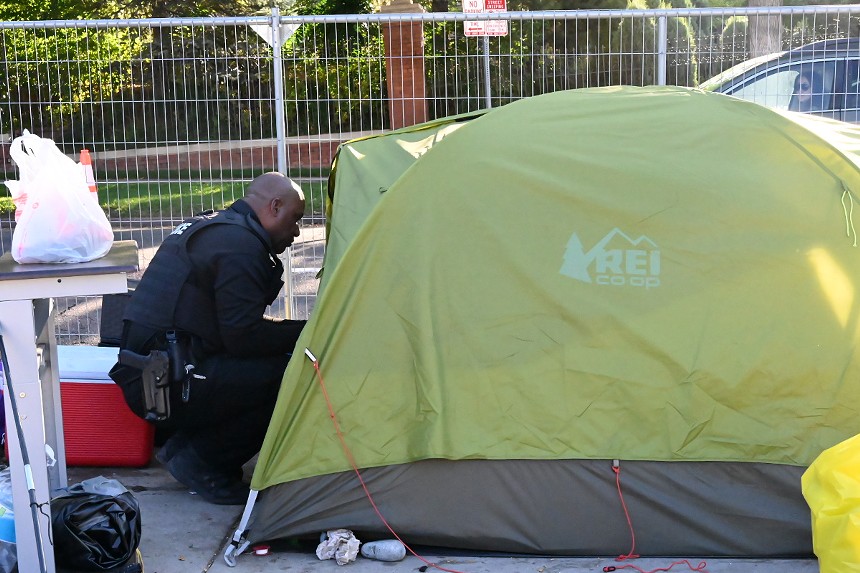 A Denver Police officer talks to a man in a tent.