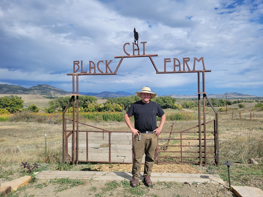 farmer stands in front of iron gate with view