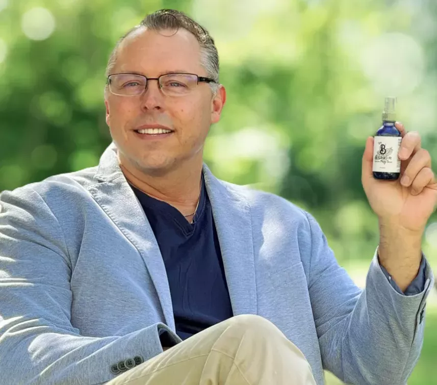 a man in a suit jacket holding a spray bottle