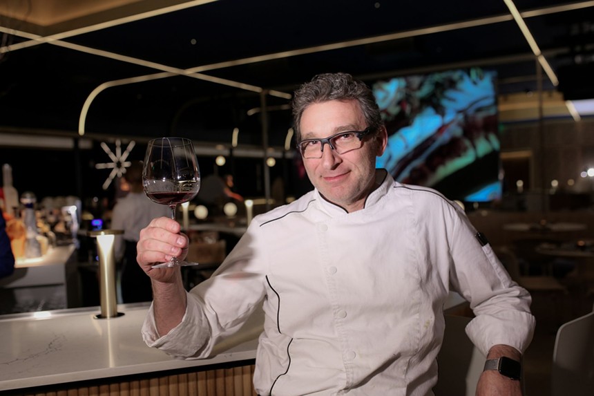 a man in a chef's coat holding a glass of wine