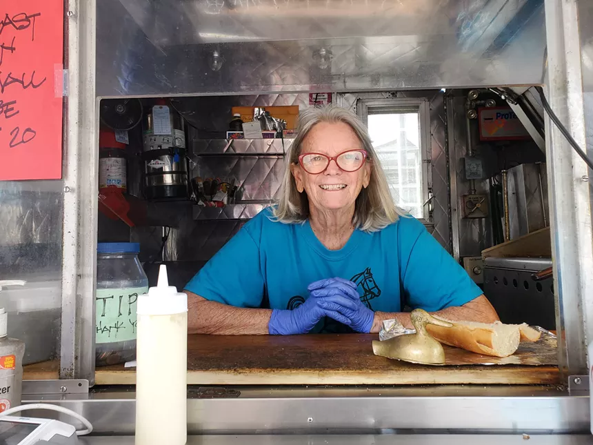 a woman standing in the window of a food cart