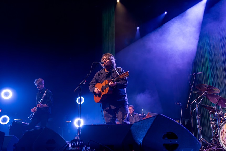 man playing acoustic guitar on stage with blue lighting